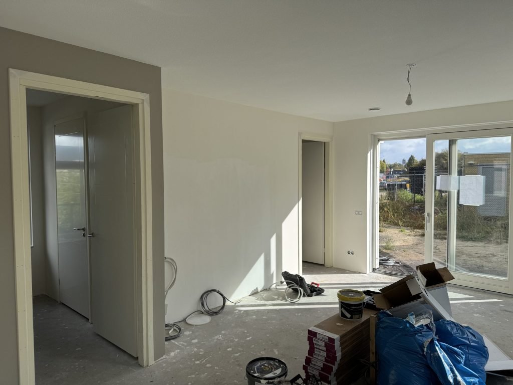 Nieuwbouwwoonkamer tijdens de afwerking, met materiaal en dozen op de vloer