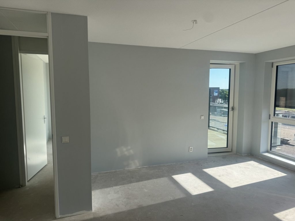 Lege nieuwbouwkamer met kale grijze wanden en een betonvloer, klaar voor de afwerking